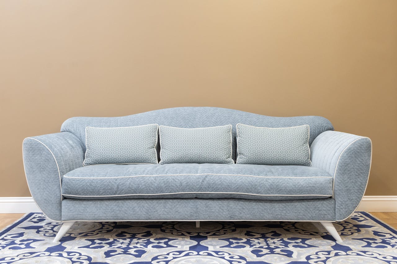 Stylish blue sofa with cushions on patterned carpet, perfect for a modern, cozy living space.